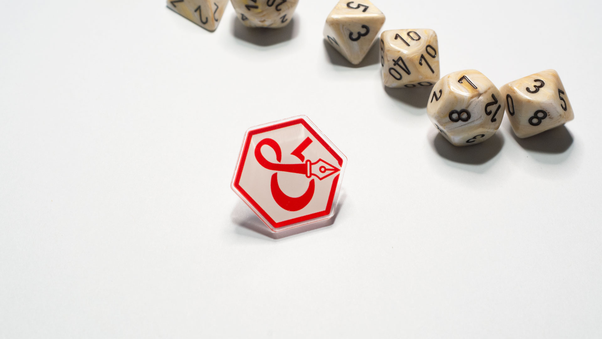 Acrylic pin of ampersand logo with dice behind it.