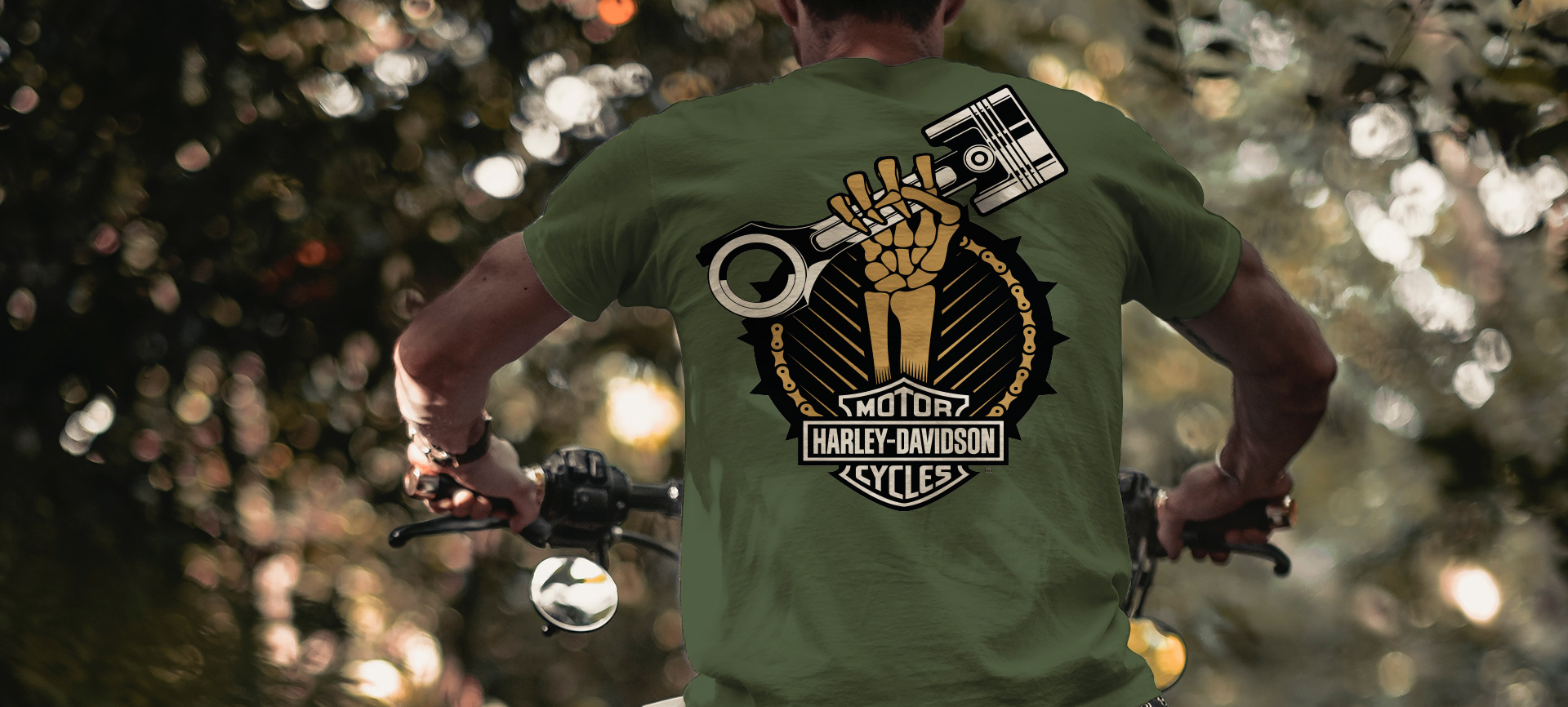 Man on motorcycle wearing a shirt with a skeleton hand holding a piston.